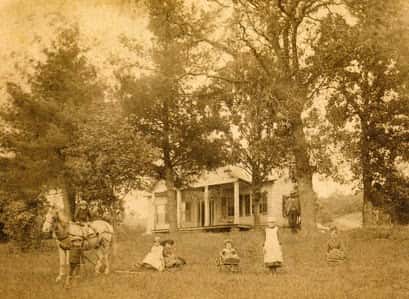 A historical photograph of the house at Aldebaran Farm with family and a horse